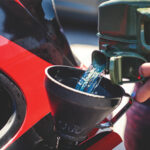 Image of fuel being poured into a car from a fuel can.