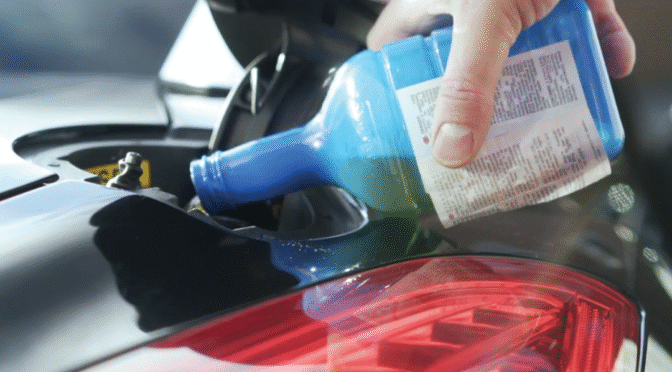Fuel additive being poured into a cars fuel tank