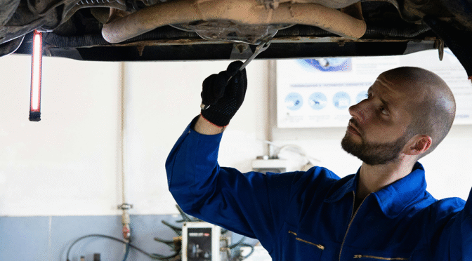 Mechanic looking at the underside of a vehicle